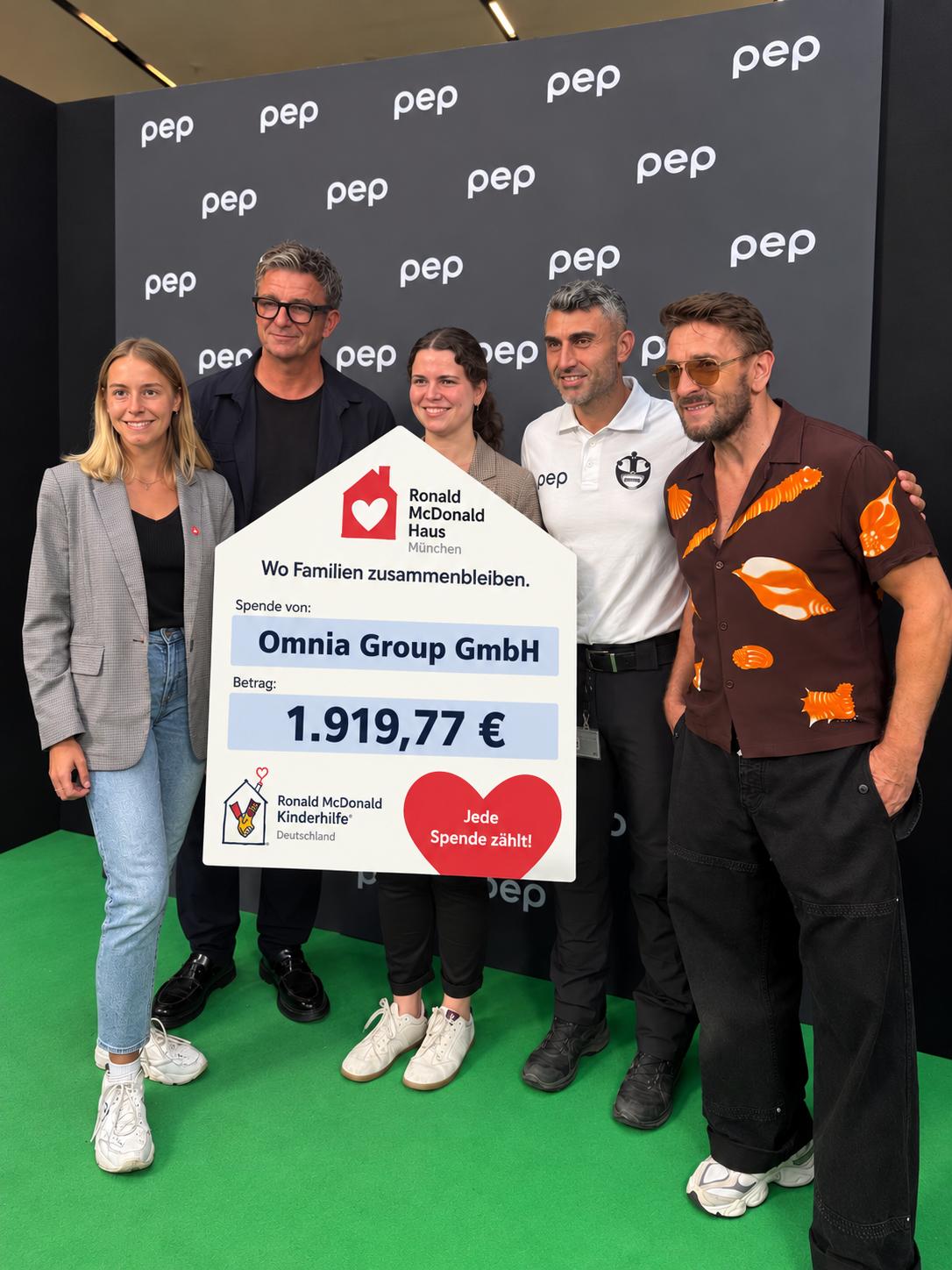 Spendenübergabe der Omnia Group GmbH mit einer Spendentafel über 1.919,77 Euro für das Ronald McDonald Haus München
